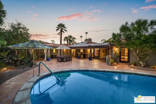 pool at dusk featuring a patio area