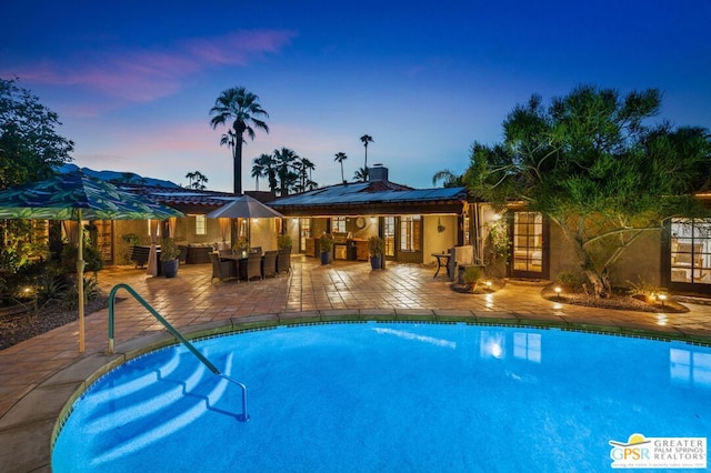 pool at dusk with a patio area