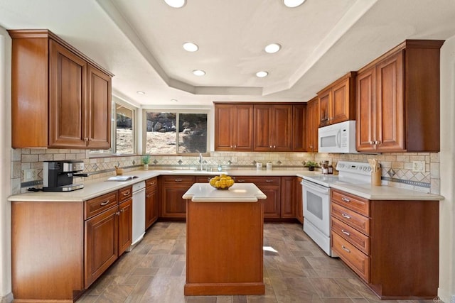 kitchen featuring white appliances, a center island, decorative backsplash, sink, and a raised ceiling