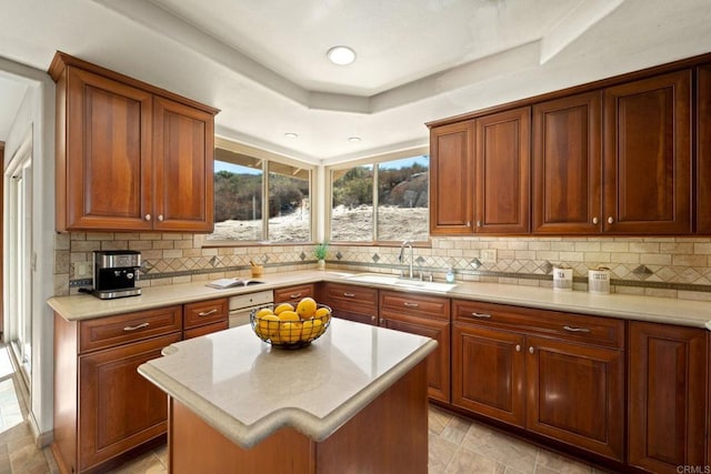 kitchen featuring sink, a center island, decorative backsplash, and a raised ceiling