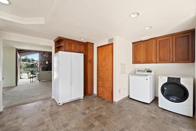 clothes washing area featuring cabinets, carpet flooring, and washer and clothes dryer