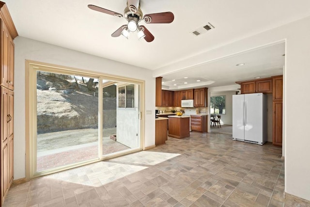 kitchen with ceiling fan, a kitchen island, and white appliances