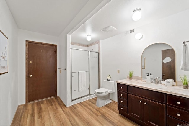 bathroom with hardwood / wood-style flooring, toilet, vanity, and a shower with door