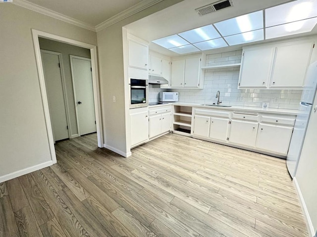 kitchen with sink, backsplash, white cabinets, light wood-type flooring, and oven