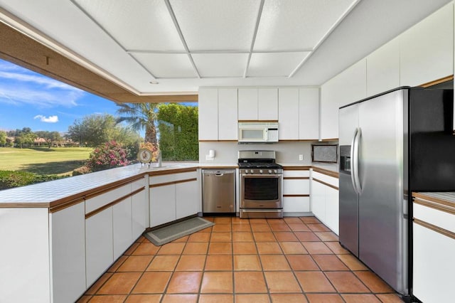 kitchen with sink, white cabinets, stainless steel appliances, and light tile patterned flooring