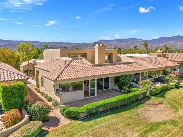 back of property with a mountain view and a lawn