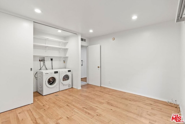 laundry area with washer and dryer and light hardwood / wood-style flooring