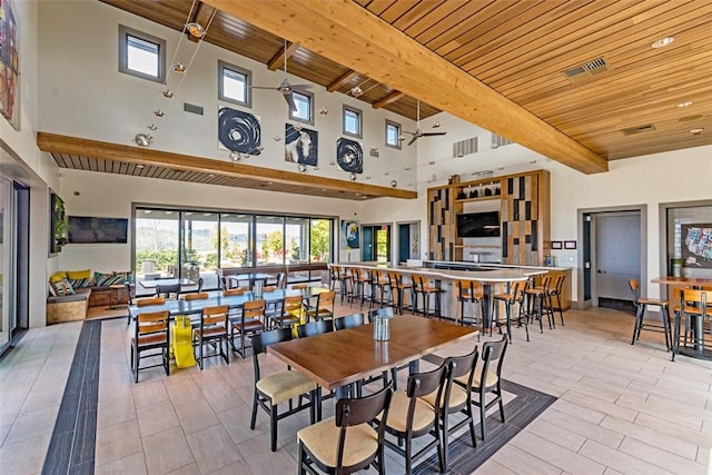 dining area with wood ceiling, a towering ceiling, ceiling fan, and beam ceiling