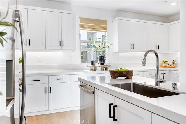 kitchen featuring sink, white cabinets, light hardwood / wood-style flooring, and stainless steel appliances