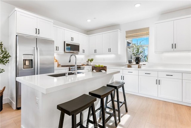 kitchen with white cabinets, appliances with stainless steel finishes, and a kitchen island with sink