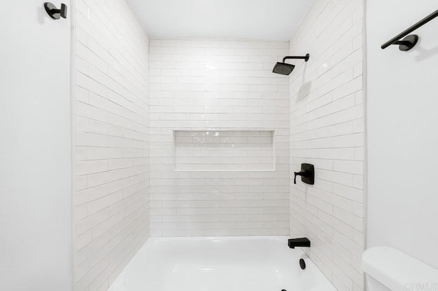 bathroom with toilet and tiled shower / bath