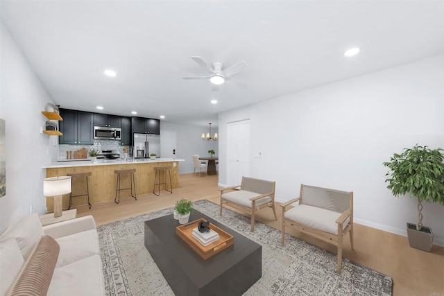 living room featuring light hardwood / wood-style floors and ceiling fan with notable chandelier