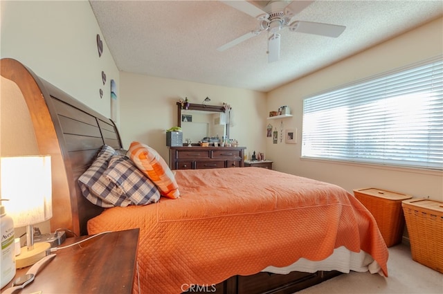 carpeted bedroom featuring ceiling fan and a textured ceiling