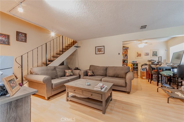 living room with track lighting, light hardwood / wood-style floors, and a textured ceiling