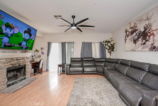 living room with wood-type flooring, ceiling fan, and a fireplace