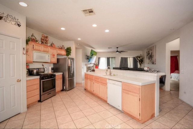 kitchen featuring stainless steel appliances, light brown cabinetry, sink, and kitchen peninsula