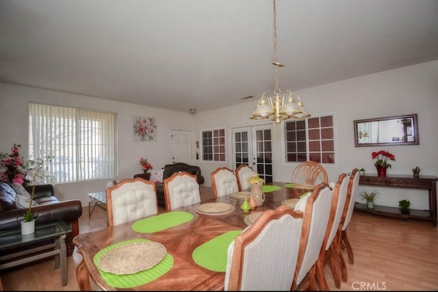 dining room with french doors, a chandelier, and light hardwood / wood-style flooring