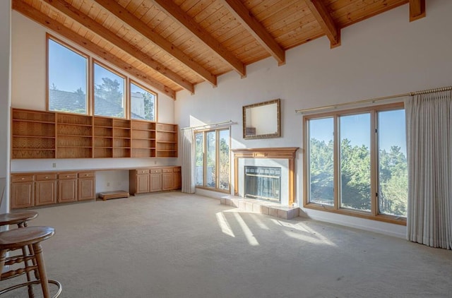 unfurnished living room featuring high vaulted ceiling, light carpet, and built in desk