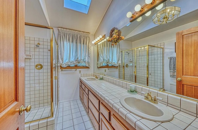 bathroom with vanity, a shower with shower door, lofted ceiling with skylight, and tile patterned floors