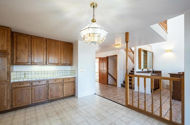 kitchen featuring a chandelier, pendant lighting, and tile countertops