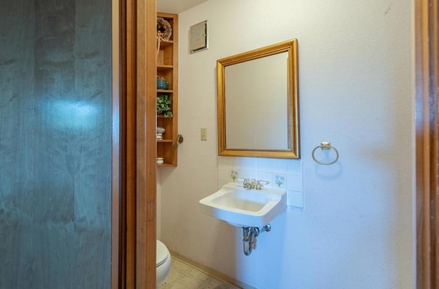 bathroom with sink, backsplash, and toilet