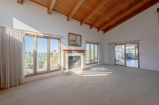 unfurnished living room with beamed ceiling, wood ceiling, high vaulted ceiling, light colored carpet, and a tiled fireplace