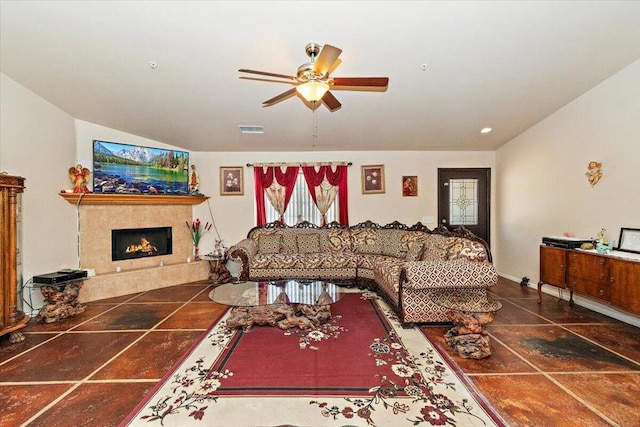 living room featuring ceiling fan and a tiled fireplace