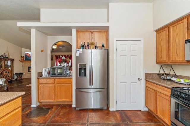 kitchen featuring stainless steel appliances, ceiling fan, and a fireplace