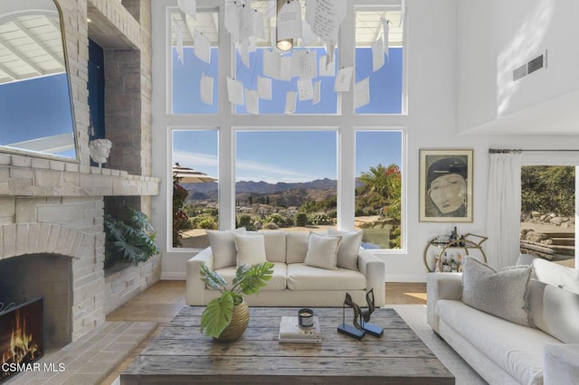 living room with wood-type flooring, a mountain view, a healthy amount of sunlight, and a brick fireplace