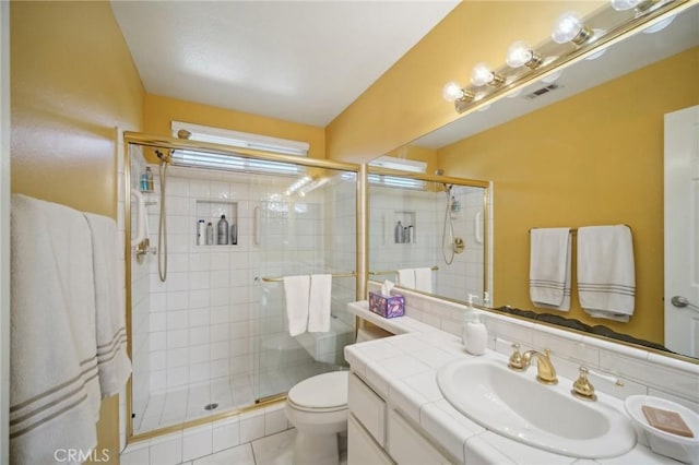 bathroom featuring vanity, toilet, a shower with shower door, and tile patterned flooring