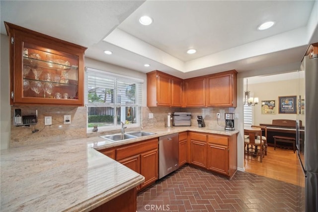 kitchen featuring pendant lighting, a raised ceiling, sink, appliances with stainless steel finishes, and tasteful backsplash