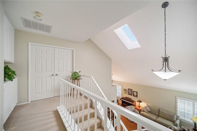 hall featuring lofted ceiling with skylight and light carpet