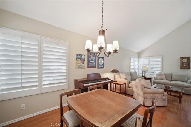 dining room featuring hardwood / wood-style flooring, vaulted ceiling, and a notable chandelier