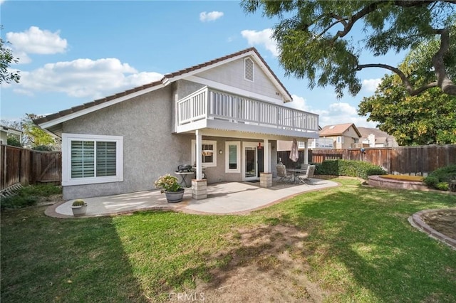 rear view of property featuring a lawn, a patio, and a balcony