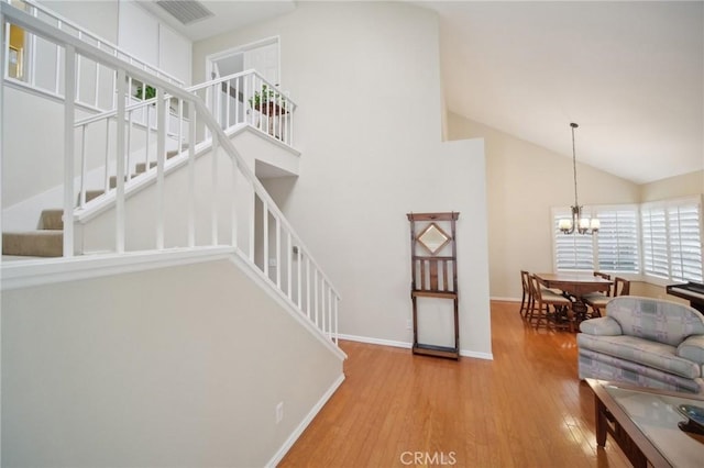 living room with a notable chandelier, high vaulted ceiling, and hardwood / wood-style floors