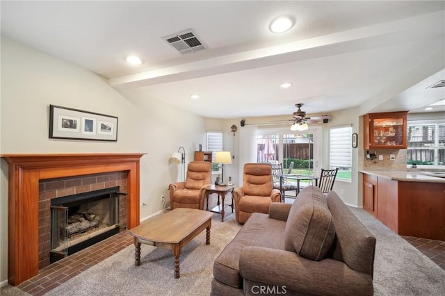 living room featuring carpet floors, beamed ceiling, and a brick fireplace