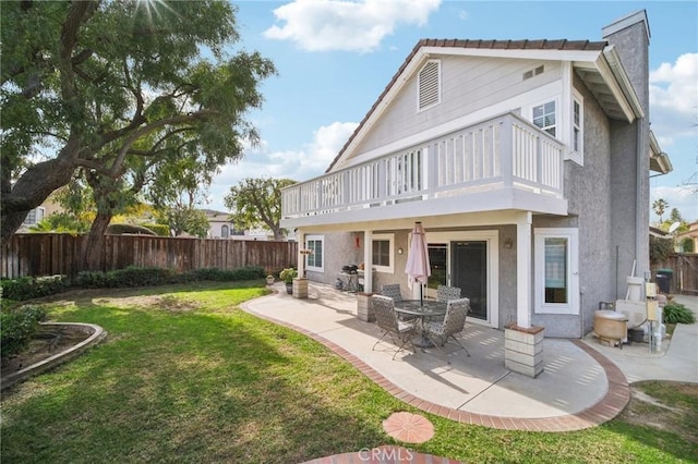 rear view of property featuring a balcony, a patio, and a yard