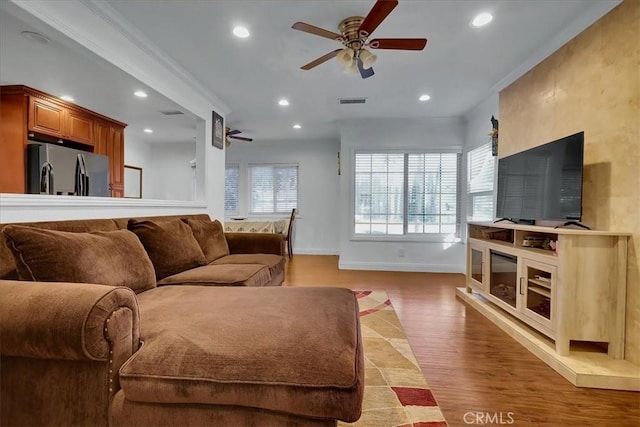 living room featuring hardwood / wood-style flooring, crown molding, and ceiling fan