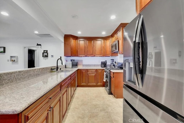 kitchen with sink, light stone countertops, kitchen peninsula, and appliances with stainless steel finishes