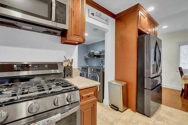 kitchen with appliances with stainless steel finishes, washer and dryer, and light tile patterned floors