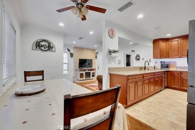 kitchen featuring sink, ceiling fan, kitchen peninsula, stainless steel appliances, and light stone countertops