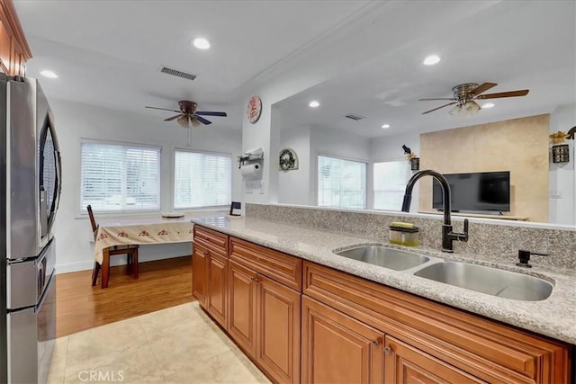 kitchen featuring light stone counters, stainless steel fridge, sink, and a wealth of natural light