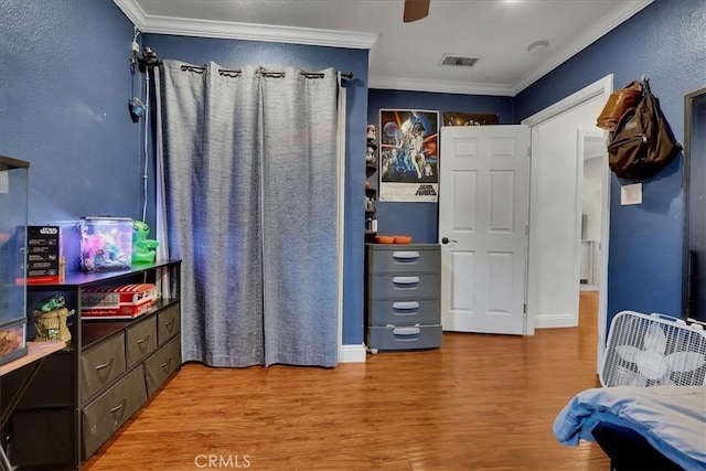 bedroom with ornamental molding, ceiling fan, and light wood-type flooring