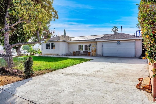 ranch-style home with a garage, a front yard, and solar panels