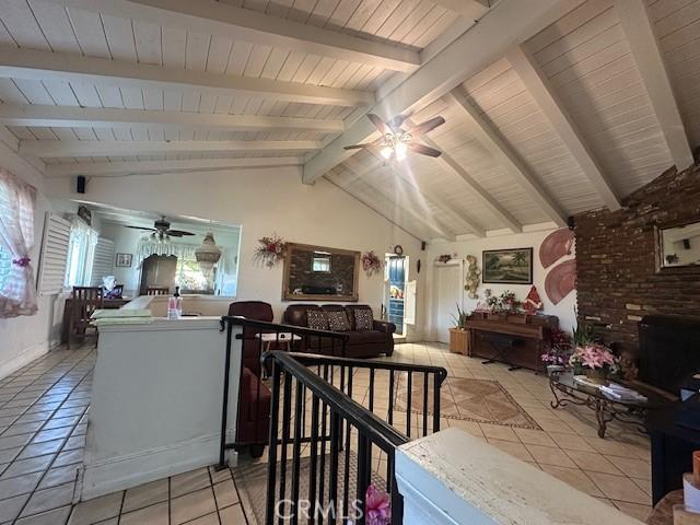 living room featuring ceiling fan, vaulted ceiling with beams, and light tile patterned flooring