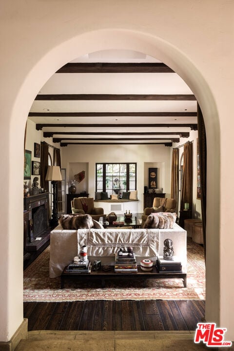 bedroom featuring hardwood / wood-style flooring, beam ceiling, and a fireplace