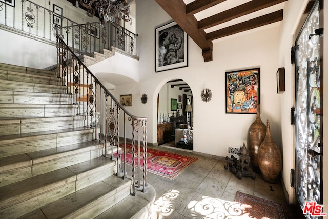 foyer with beamed ceiling and a high ceiling