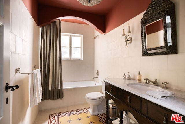 full bathroom with tiled shower / bath combo, tile patterned flooring, vanity, tile walls, and toilet