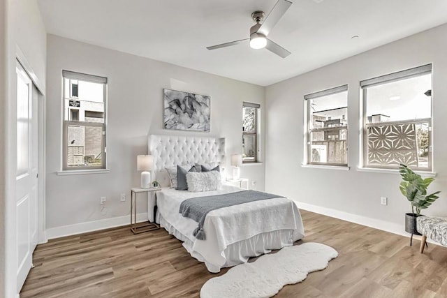 bedroom featuring hardwood / wood-style flooring, ceiling fan, and multiple windows