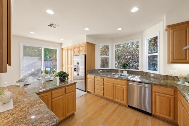 kitchen featuring stainless steel appliances, a healthy amount of sunlight, sink, and dark stone counters